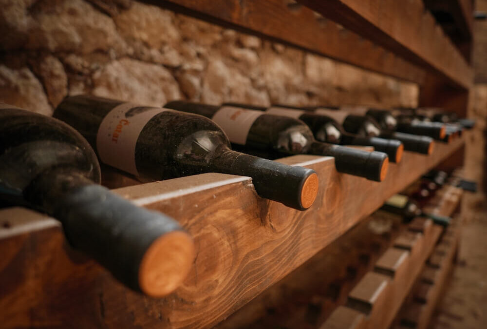 close up image of wine bottles on shelves in cellar